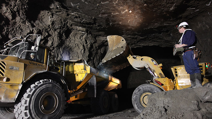 Mining employee uses a remote control to load ore into an eco-friendly, low-emission biodiesel haul truck.