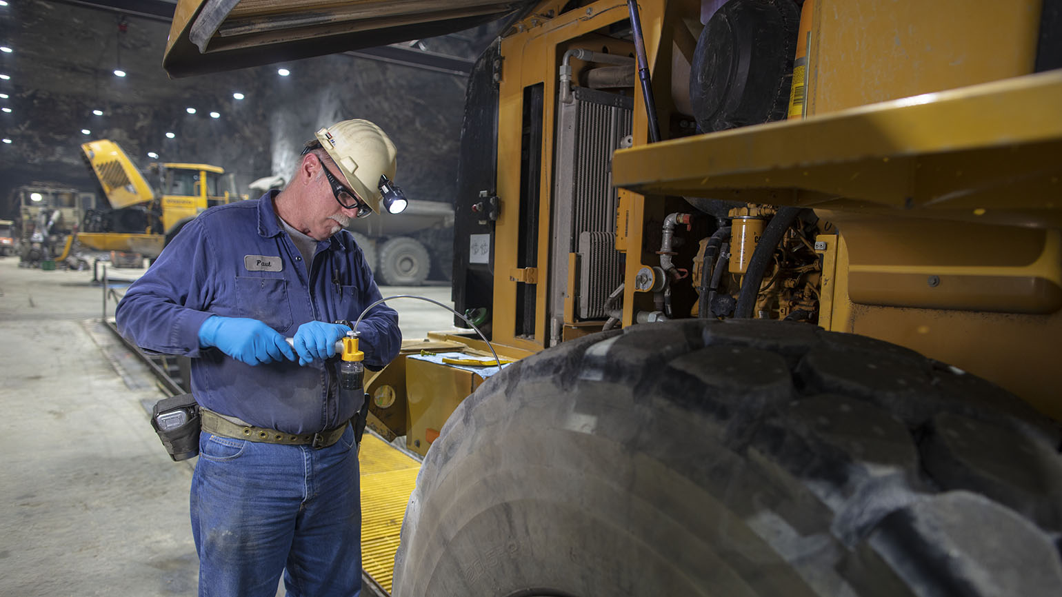 Maintenance personnel checks the lubricant of a haul truck as part of a maintenance program.
